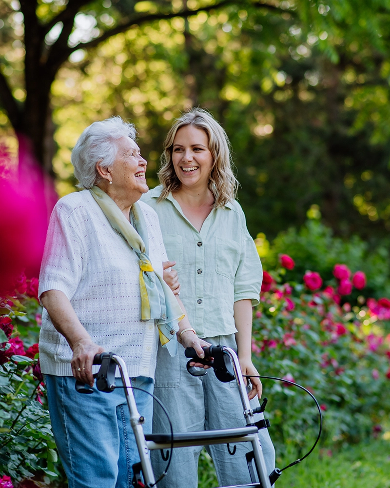 woman walking with an older woman using a walker